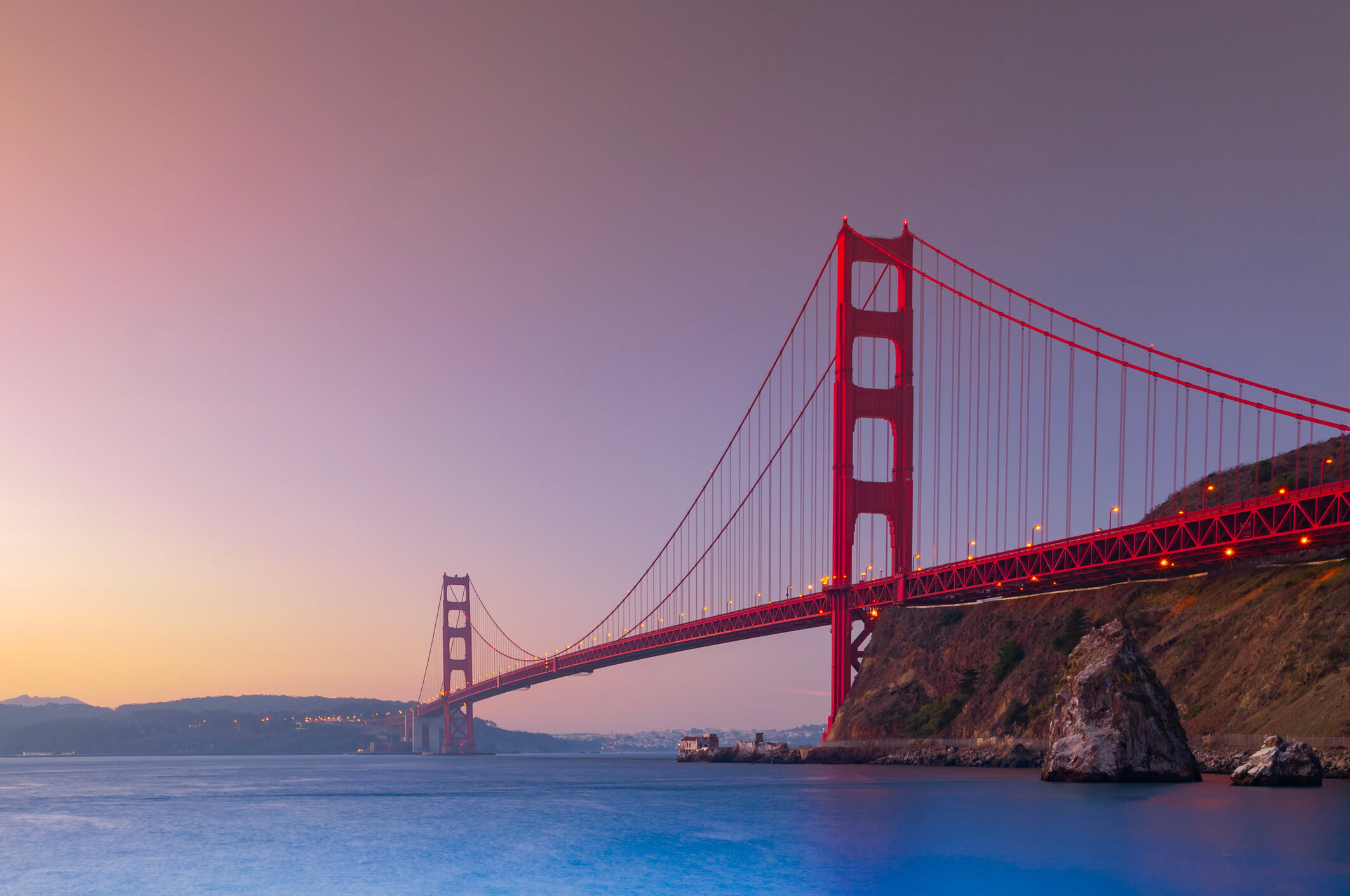 The iconic Golden Gate Bridge stretching over the San Francisco Bay at sunset.